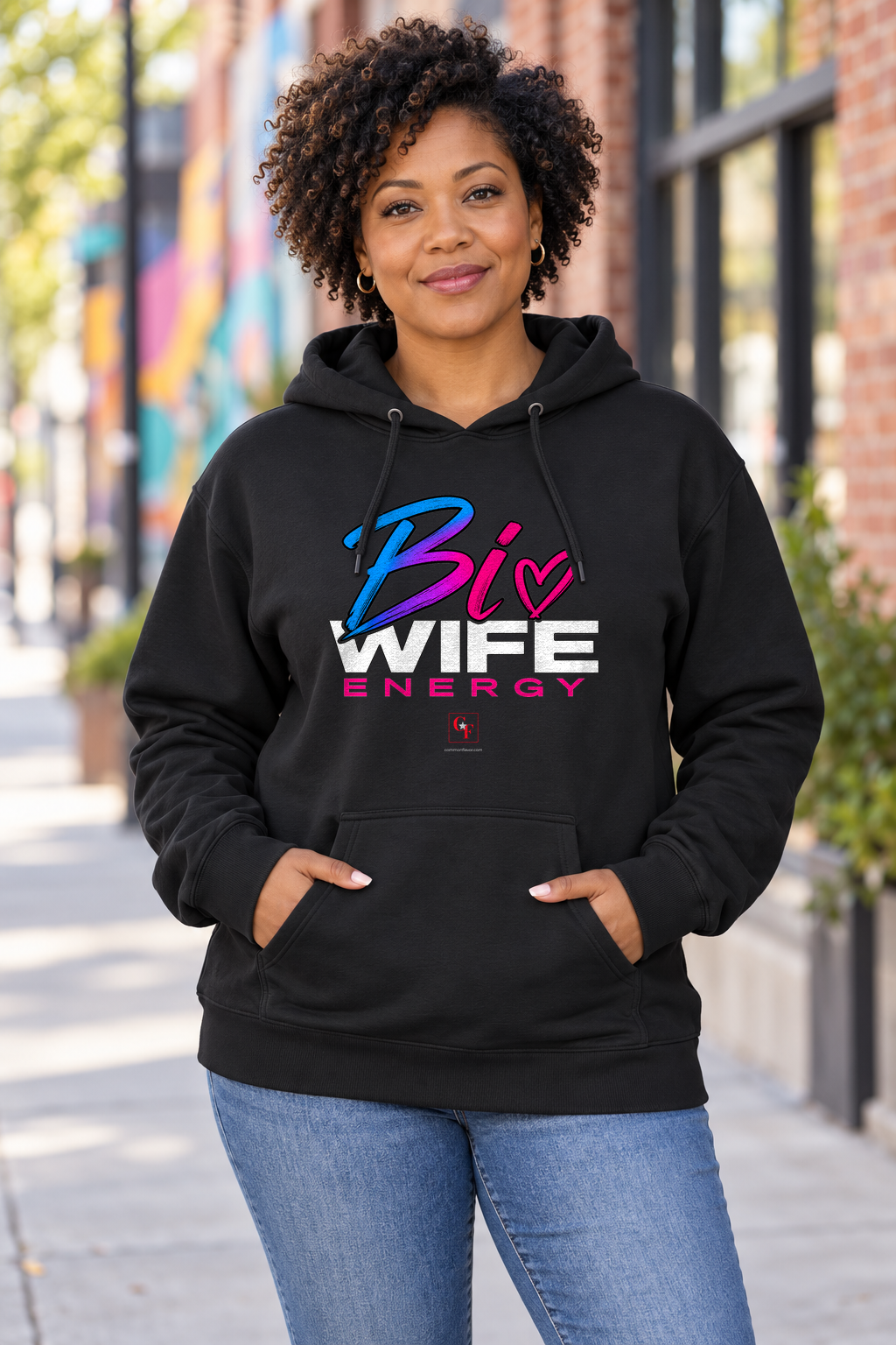 Woman wearing the Black Bi Wife Energy hoodie in an outdoor lifestyle setting